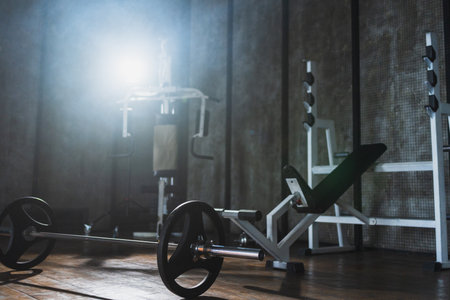 Empty gym workout area health club. Dark interior of gym with fitness equipment barbell. Weights of fitness sports for exercise. Machines tools for exercising. Training for strength building wellnessの写真素材
