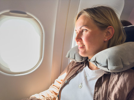 Passenger woman is flying in plane. Girl sitting in airplane looking out window going on trip vacation travel. Traveling female inside plane enjoying flight. Traveling girlの写真素材