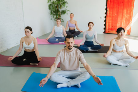Yoga mindfulness meditation. Group of sporty people doing exercise in studio for class for yoga wellness mindfulness meditation. Men women practicing yoga sitting in lotus pose meditating relaxingの写真素材