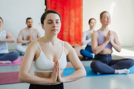 Yoga mindfulness meditation. Group of sporty people doing exercise in studio for class for yoga wellness mindfulness meditation. Men women practicing yoga sitting in lotus pose meditating relaxingの写真素材