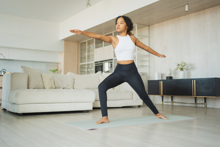Yoga fitness workout training. Healthy African girl practicing yoga at home. Woman training Pilates doing sports exercise on yoga mat indoor. Girl have training workout for weight loss. Sport fitnessの写真素材