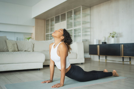 Yoga fitness workout training. Healthy African girl practicing yoga at home. Woman training Pilates doing sports exercise on yoga mat indoor. Girl have training workout for weight loss. Sport fitnessの写真素材