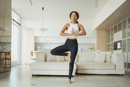 Yoga fitness workout training. Healthy African girl practicing yoga at home. Woman training Pilates doing sports exercise on yoga mat indoor. Girl have training workout for weight loss. Sport fitnessの写真素材