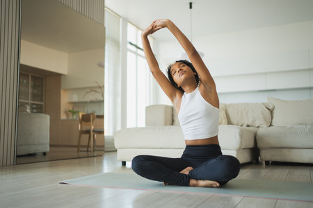 Yoga fitness workout training. Healthy African girl practicing yoga at home. Woman training Pilates doing sports exercise on yoga mat indoor. Girl have training workout for weight loss. Sport fitnessの写真素材