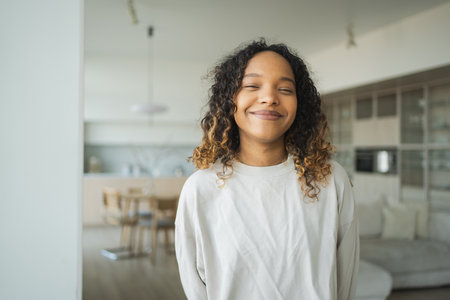 Beautiful African American girl with afro hairstyle smiling. Close up portrait of young happy black girl. Young African woman with curly hair laughing. Freedom happiness carefree happy people conceptの写真素材