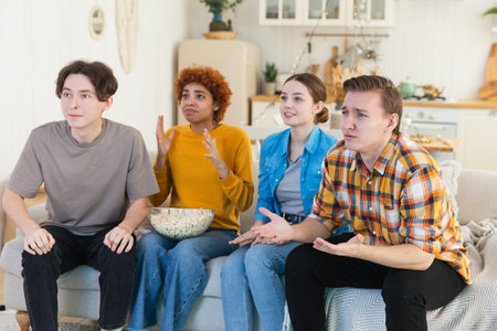 Group of friends watching sport match soccer football game on tv. Happy football fans celebrating victory at home. Friendship sports entertainment concept. Diverse buddies having fun together at homeの写真素材