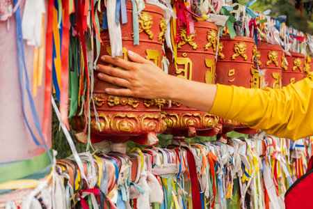 Person pilgrim female hand touching turning spinning Buddhist prayer wheel at Buddhist monastery. Prayer wheels in Buddhist stupa temple. Buddhism religion conceptの写真素材