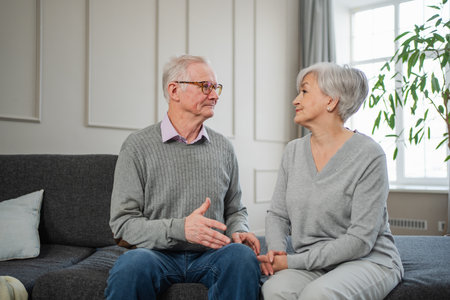 Senior adult mature couple talking at home. Mid age old husband and wife speaking smiling laughing enjoying time together. Grandmother grandfather spending time together. Family moment love and careの写真素材