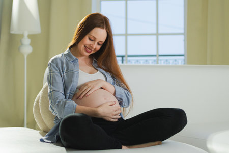 Pregnancy motherhood people expectation future. Pregnant woman touching big belly sitting on couch...