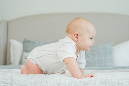 Happy baby. Cute little newborn girl with smiling face crawling on bed in bedroom. Infant baby resting playing lying down on blanket at home. Motherhood happy child childcare conceptの写真素材