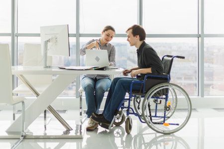 Colleagues business people woman man in chair for people with disability working on office. Startup business group team working together. Corporate professional team discussing project ideasの写真素材