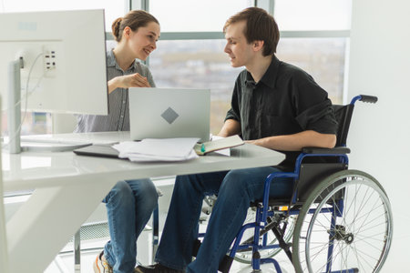 Colleagues business people woman man in chair for people with disability working on office. Startup business group team working together. Corporate professional team discussing project ideasの写真素材