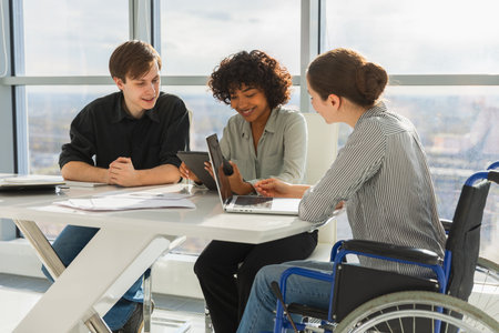 Teamwork brainstorm. Diverse multiracial colleagues woman in chair for people with disability working together. Group of people sitting in creative office discussing business. Young professional teamの写真素材