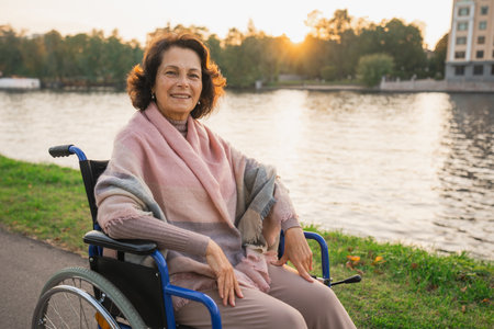 Happy senior woman in wheelchair smiling enjoying freedom walking on road in city park outdoor. Old cheerful positive woman in chair for people with disability. Disability disease rehabilitationの写真素材