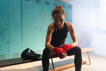 Women self defense girl power. Woman fighter preparing for fight wrapping hands with red boxing wraps sports protective bandages. Strong hands ready for fight active exercise sparring workout trainingの写真素材