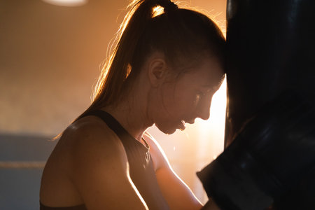 Women self defense girl power. Strong woman fighter resting after fight training on boxing ring. Strong girl tired after punching boxing bag. Training day in gym. Strength fit body workout trainingの写真素材