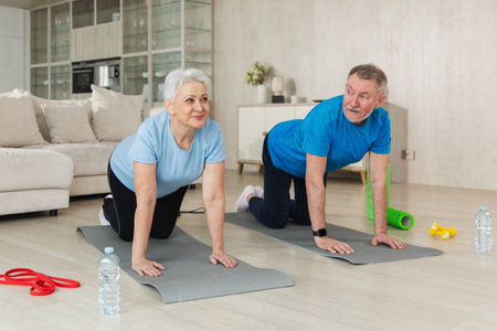 Fitness workout training. Senior adult mature healthy fit couple doing sports exercise on yoga mat on floor at home. Mid age old husband wife have training workout. Health care healthy lifestyleの写真素材