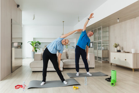 Fitness training. Senior mature healthy fit couple doing sports exercise at home. Mid age husband wife have training workout. Health care healthy lifestyle. Workout rehabilitation for old man womanの写真素材