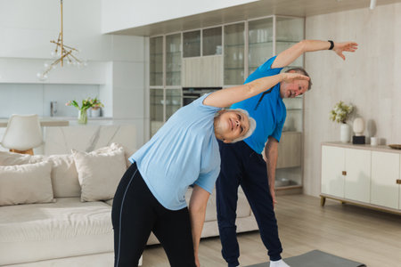Fitness training. Senior mature healthy fit couple doing sports exercise at home. Mid age husband wife have training workout. Health care healthy lifestyle. Workout rehabilitation for old man womanの写真素材