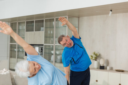 Fitness training. Senior mature healthy fit couple doing sports exercise at home. Mid age husband wife have training workout. Health care healthy lifestyle. Workout rehabilitation for old man womanの写真素材