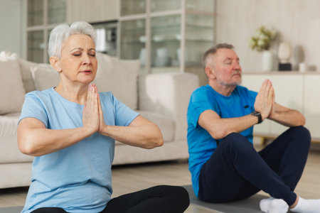 Yoga mindfulness meditation. Senior adult mature couple practicing yoga at home. Mid age old husband wife sitting in lotus pose on yoga mat meditating relaxing. Family doing breathing practiceの写真素材