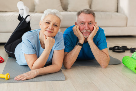 Fitness workout home training. Senior adult mature healthy fit couple resting after sports exercise on yoga mat at home. Mid age old husband wife have training workout. Health care healthy lifestyleの写真素材
