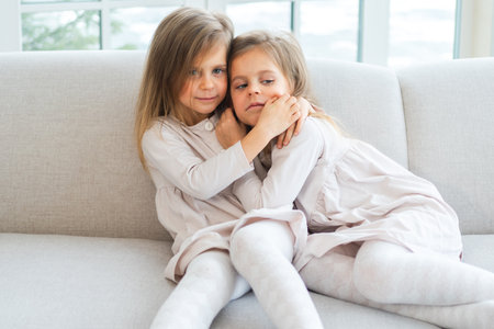 Happy family sisterly love. Two funny little twin sisters girls hugging with love care playing...