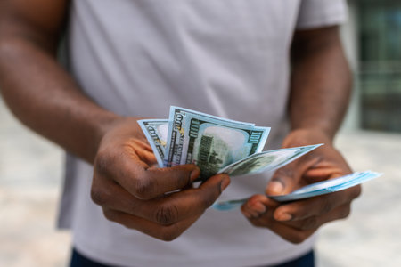 Man hands holding money dollar bills on urban street outdoor. Businessman hands counting currency money outdoors near office bank building. Unrecognizable man holding cash. Finance economy bankingの写真素材