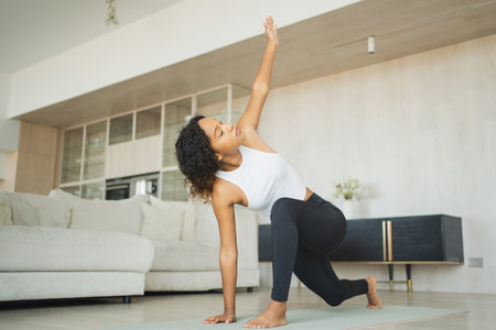 Yoga fitness workout training. Healthy African girl practicing yoga at home. Woman training Pilates doing sports exercise on yoga mat indoor. Girl have training workout for weight loss. Sport fitnessの写真素材