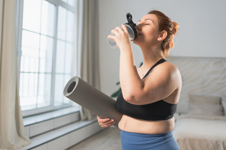 Yoga fitness sport workout training. Woman holding yoga mat drinking bottle water ready for...