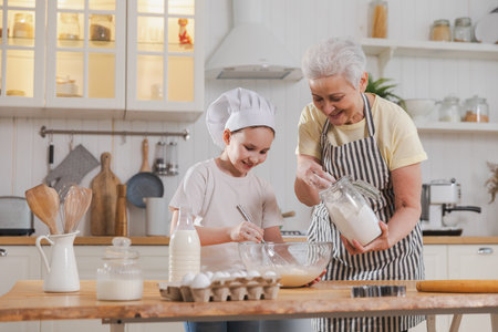 Happy family in kitchen. Grandmother and granddaughter child cook in kitchen together. Grandma...
