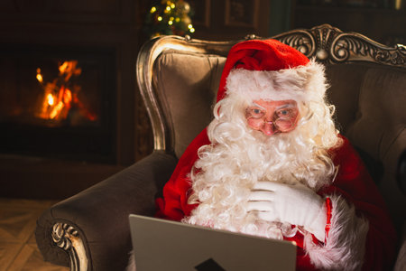 Merry Christmas. Santa Claus with laptop reading letters from children typing buying presents gifts...
