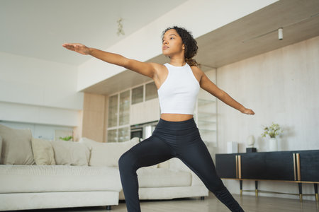 Yoga fitness workout training. Healthy African girl practicing yoga at home. Woman training Pilates doing sports exercise on yoga mat indoor. Girl have training workout for weight loss. Sport fitnessの写真素材