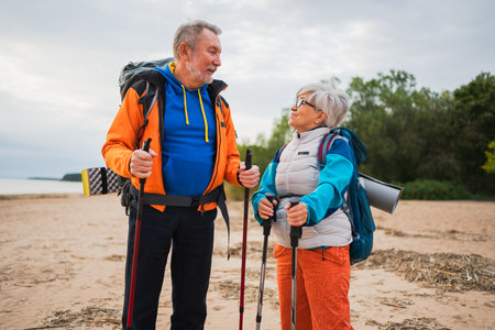Hiking tourism adventure. Senior couple man woman enjoying outdoor recreation hiking on beach. Happy old people backpackers hikers enjoy walking hike trekking tourism active vacation beauty of natureの写真素材