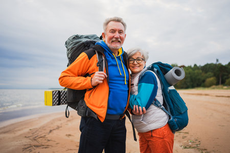 Hiking tourism adventure. Senior couple man woman enjoying outdoor recreation hiking on beach. Happy...