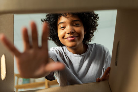 Inside of cardbox bottom view. African girl unpacking delivery looking in box. Woman opening carton box. Female getting parcel looking at delivered goods items. Satisfied client positive feedbackの写真素材