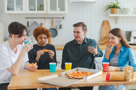 Home party. Overjoyed diverse friends eating ordered pizza for home party. Happy group multiracial...