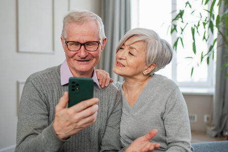 Video call. Happy senior couple woman man with smartphone having video call. Mature old grandmother grandfather talking speaking online. Older generation modern tech usage. Virtual meeting online chatの写真素材