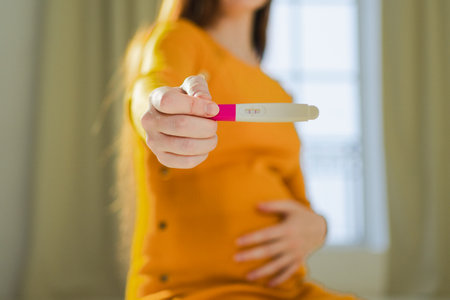Woman hand holding positive pregnancy test. Pregnant woman with big belly expecting baby undergo fertility infertility treatment IVF. Pregnancy motherhood future maternity parenthood new lifeの写真素材