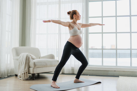 Pregnancy yoga fitness workout training. Pregnant woman practicing yoga at home. Pregnant girl doing sports exercise on yoga mat indoor. Woman with big belly have fitness training practicing asanaの写真素材