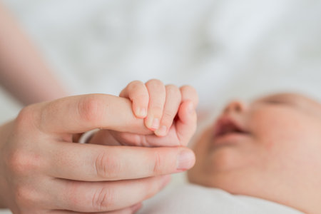 Happy family. Tiny newborn infant baby little hand on mother hand palm. Newborn baby holding parent finger after birth. Mom baby at home. Support protection of new life. Handle with careの写真素材