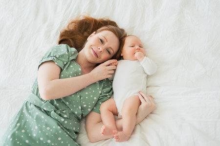 Happy family at home. Mother playing with little toddler child on bed. Mom baby relax playing having...