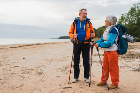 Hiking tourism adventure. Senior couple man woman enjoying outdoor recreation hiking on beach. Happy old people backpackers hikers enjoy walking hike trekking tourism active vacation beauty of natureの写真素材