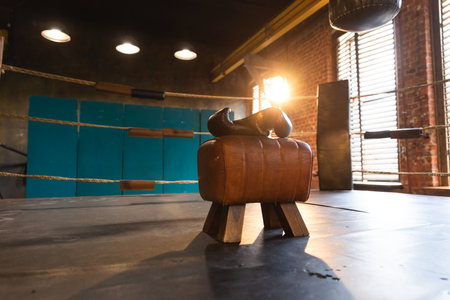 Boxing gloves lying down on boxing ring in empty gym. Equipment for fight training competition black...
