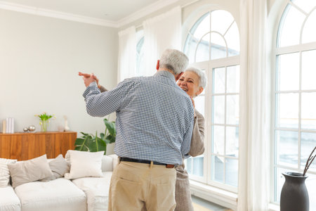 Keep moving. Romantic senior mature couple dancing to music together at home. Happy smiling family retired man woman husband wife having fun enjoying time together. Family moment love careの写真素材