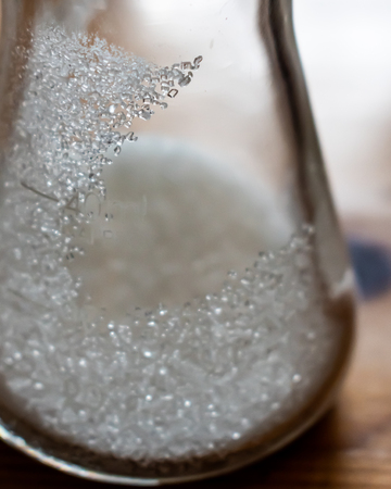 erlenmeyer flask with table sugar crystals inside. Some crystals cling to the walls of the flask...