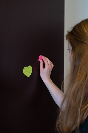 Female model placing pink generic reminder on refrigeratorの写真素材