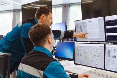 The working operator at the monitors monitors the parameters of the equipment of the chemical plant.