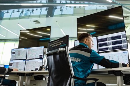 The working operator at the monitors monitors the parameters of the equipment of the chemical plant.