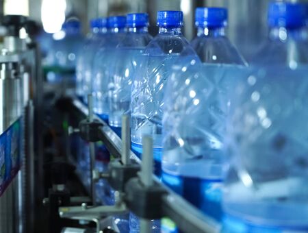 Filling line of sparkling water in a pet bottle. Mini factory for bottling water.